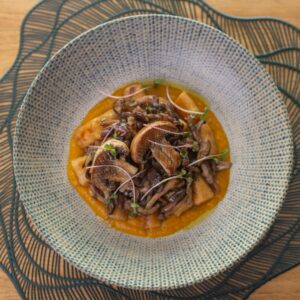 Delicious gourmet mushroom dish served in a textured bowl on a wooden table.