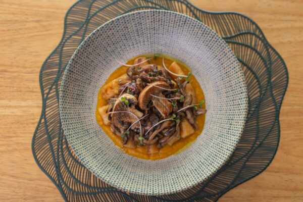 Delicious gourmet mushroom dish served in a textured bowl on a wooden table.