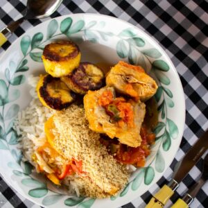 Savor a vibrant Brazilian meal featuring rice, chicken, fried plantains, and farofa on a checkered table.