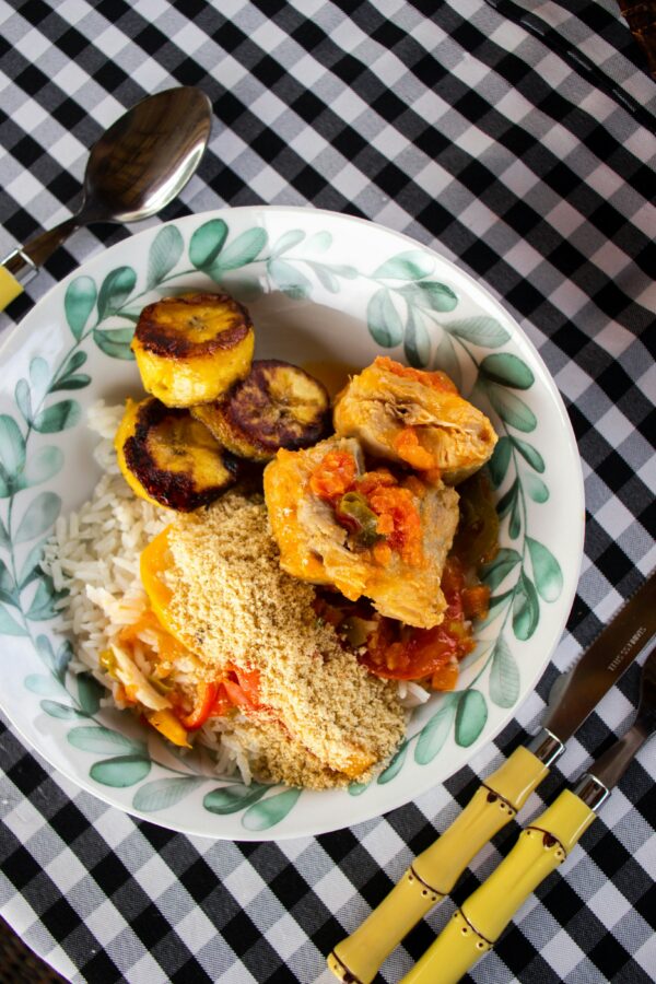 Savor a vibrant Brazilian meal featuring rice, chicken, fried plantains, and farofa on a checkered table.